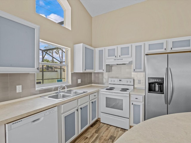 2977 Kokomo Loop, Haines City, FL 33844 - kitchen with white appliances, under cabinet range hood, tasteful backsplash, light countertops, and light wood-style floors