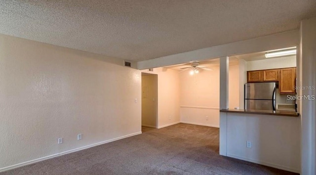 unfurnished living room featuring dark carpet, ceiling fan, and a textured ceiling