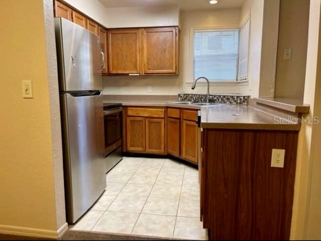 kitchen featuring light tile patterned floors, kitchen peninsula, stainless steel appliances, and sink