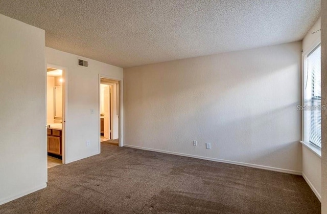 carpeted empty room featuring a textured ceiling