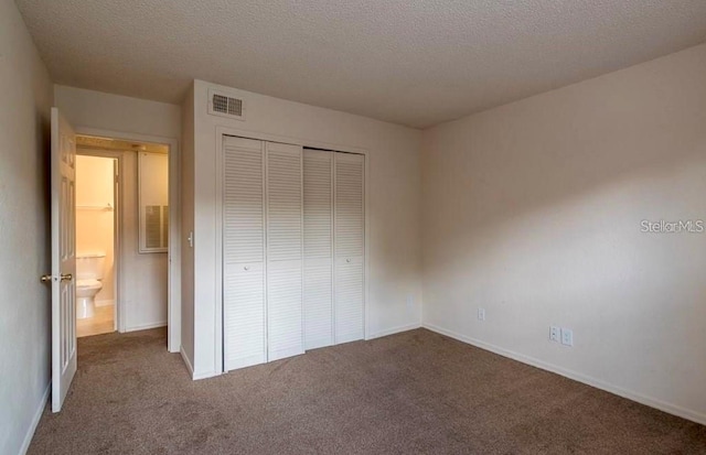 unfurnished bedroom featuring a textured ceiling, carpet flooring, and a closet