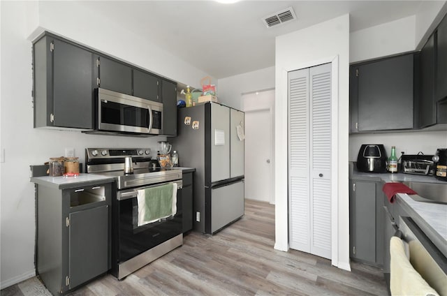 kitchen with appliances with stainless steel finishes and light hardwood / wood-style flooring