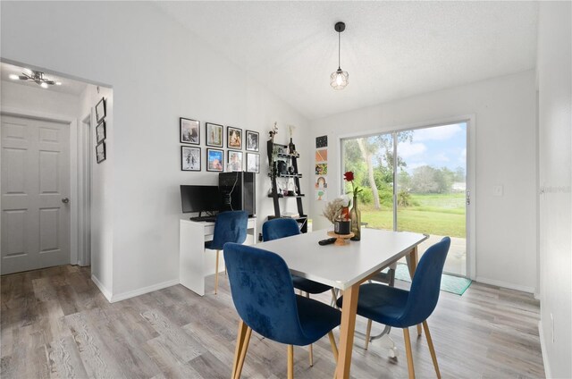 dining space featuring high vaulted ceiling, light hardwood / wood-style floors, and a textured ceiling