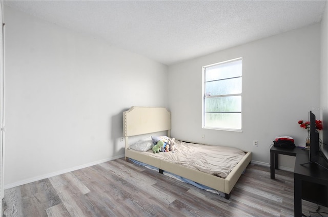 bedroom with a textured ceiling and hardwood / wood-style flooring