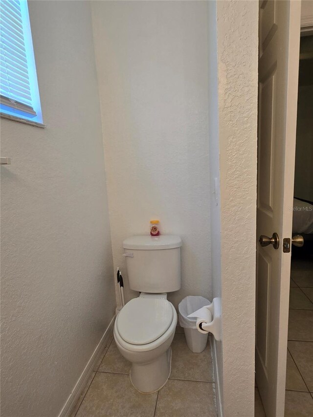 bathroom featuring tile patterned flooring, toilet, and baseboards