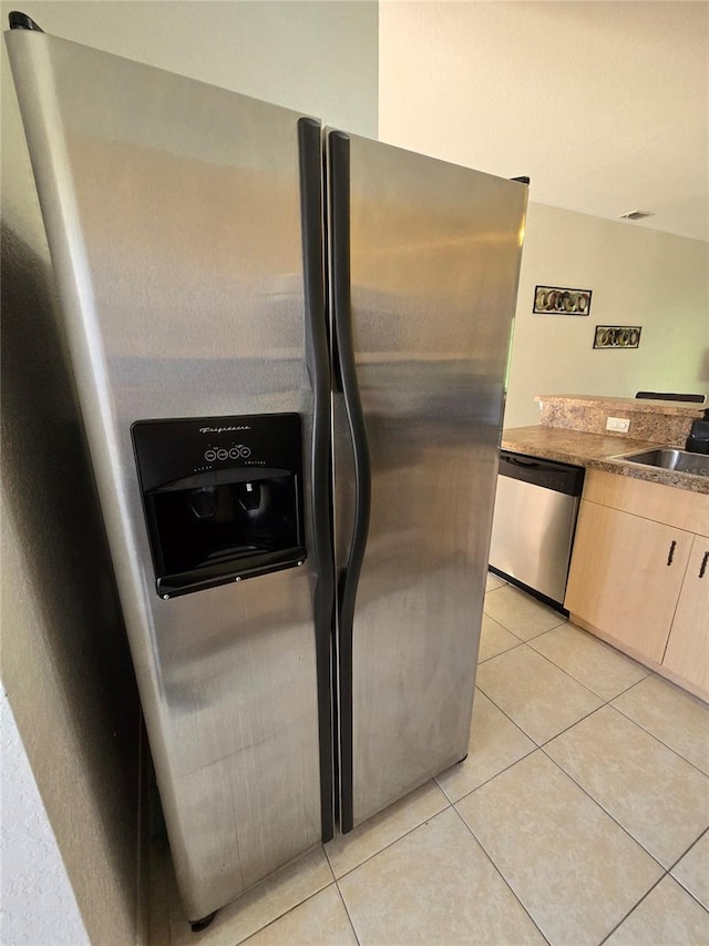 room details with light tile patterned floors, light brown cabinets, stainless steel appliances, and sink