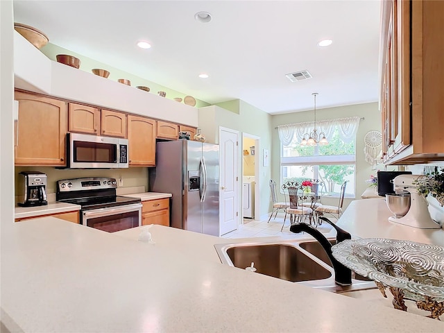 kitchen featuring a notable chandelier, light tile patterned floors, washer / clothes dryer, hanging light fixtures, and stainless steel appliances