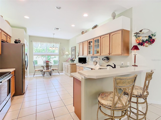 kitchen with appliances with stainless steel finishes, hanging light fixtures, kitchen peninsula, and a breakfast bar