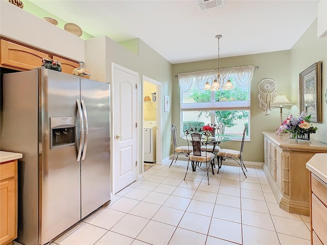 kitchen featuring decorative light fixtures, stainless steel refrigerator with ice dispenser, a notable chandelier, light tile patterned floors, and washer / clothes dryer