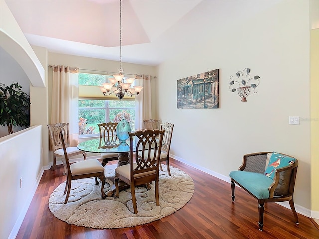 dining area with lofted ceiling, an inviting chandelier, and dark hardwood / wood-style flooring