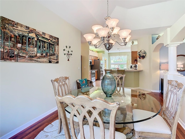 dining area featuring hardwood / wood-style floors, decorative columns, and a chandelier