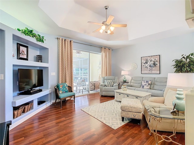 living room featuring a raised ceiling, ceiling fan, and dark hardwood / wood-style floors