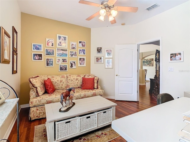 living room featuring dark wood-type flooring and ceiling fan