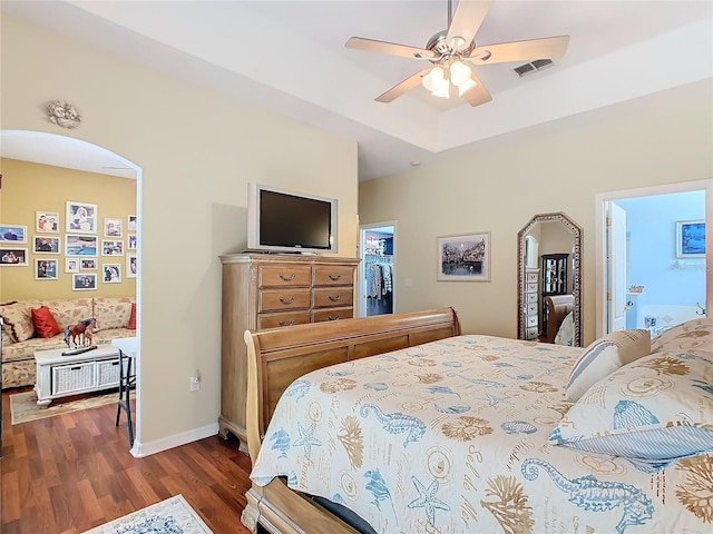 bedroom featuring hardwood / wood-style floors, a walk in closet, a closet, ceiling fan, and connected bathroom