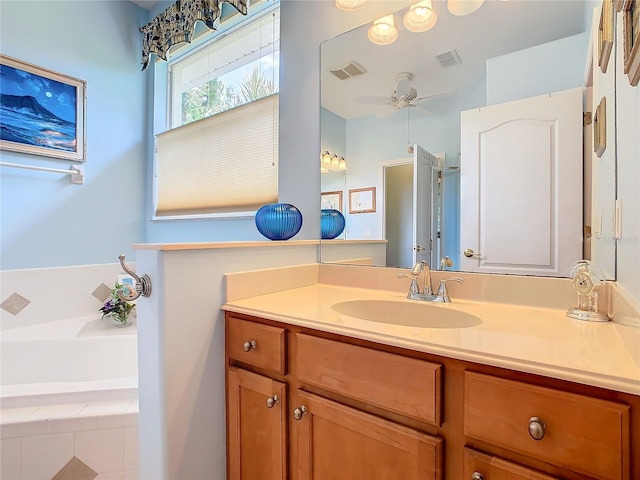 bathroom with ceiling fan, a relaxing tiled tub, and vanity