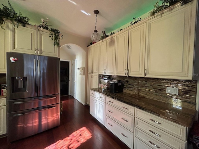 kitchen with stainless steel fridge, dark hardwood / wood-style flooring, backsplash, cream cabinetry, and dark stone countertops