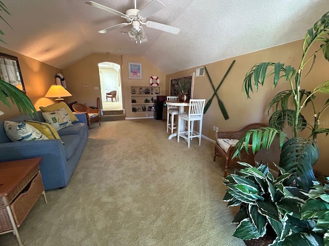 carpeted living room with ceiling fan, a textured ceiling, and vaulted ceiling