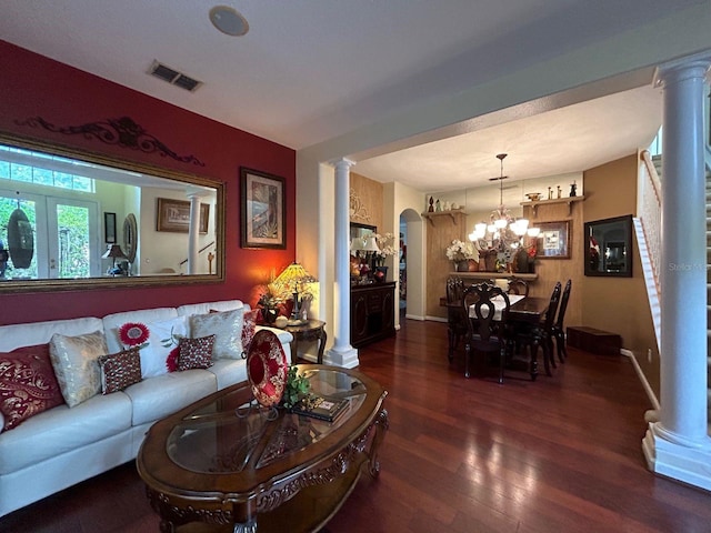 living room with decorative columns, dark hardwood / wood-style floors, and an inviting chandelier