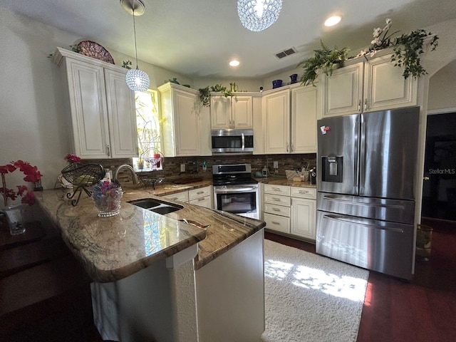 kitchen featuring tasteful backsplash, decorative light fixtures, light stone counters, kitchen peninsula, and appliances with stainless steel finishes