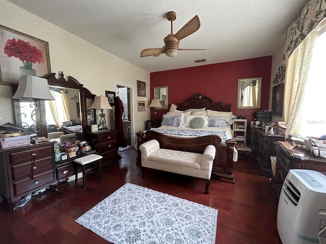 bedroom featuring dark wood-type flooring, multiple windows, ceiling fan, and a textured ceiling