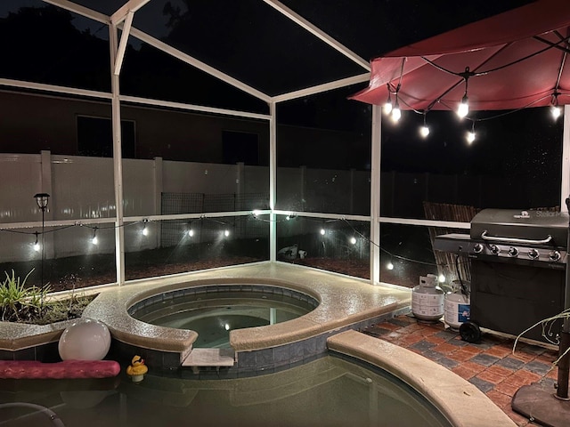 patio at night featuring a grill and an in ground hot tub