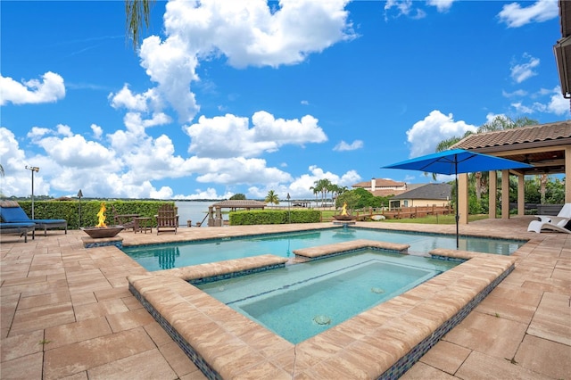 view of pool with a pool with connected hot tub, a fire pit, and a patio