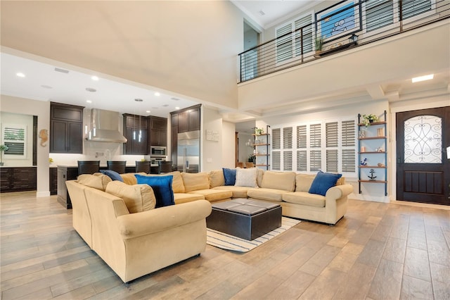 living room featuring recessed lighting, a high ceiling, and light wood finished floors