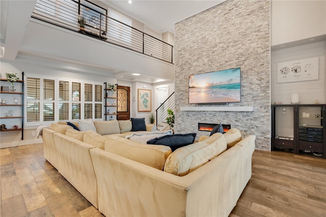 living area featuring ornamental molding, a fireplace, a high ceiling, and wood finished floors