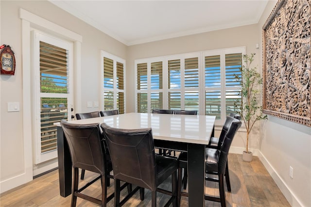 dining area with light wood-style floors, plenty of natural light, crown molding, and baseboards