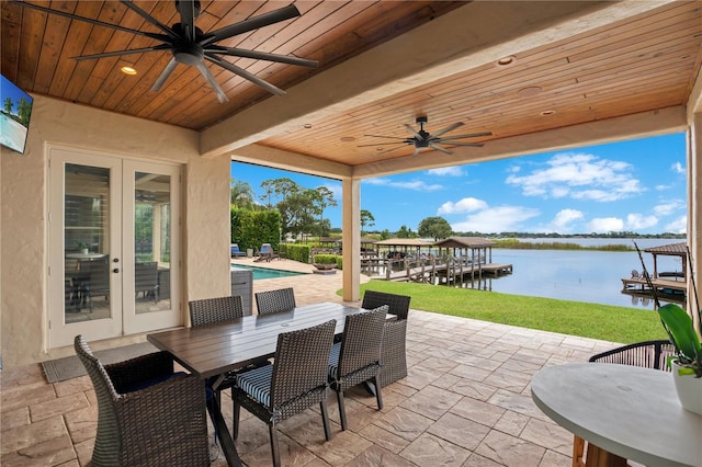 view of patio featuring french doors, a water view, a ceiling fan, a dock, and an outdoor pool