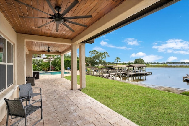 view of patio / terrace with a water view, a pool with connected hot tub, a ceiling fan, and a boat dock