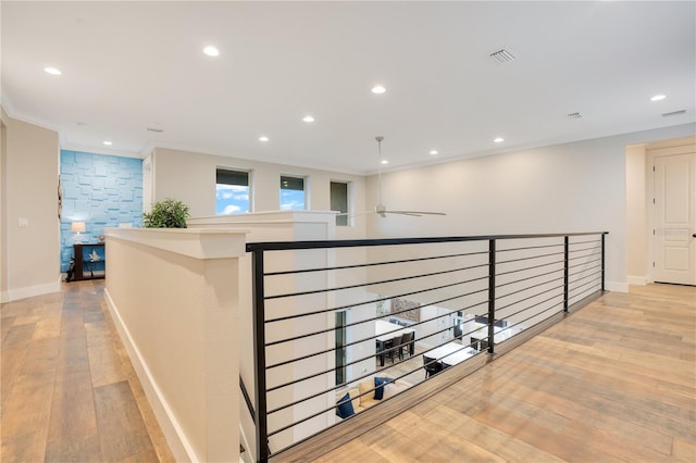 hall with light wood-style floors, recessed lighting, visible vents, and ornamental molding