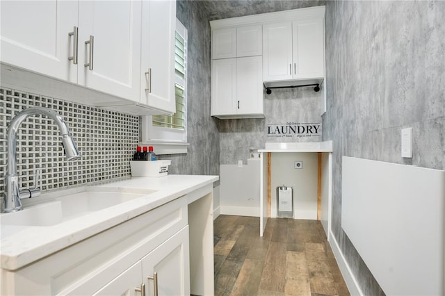 kitchen featuring tasteful backsplash, dark wood finished floors, white cabinets, light countertops, and a sink