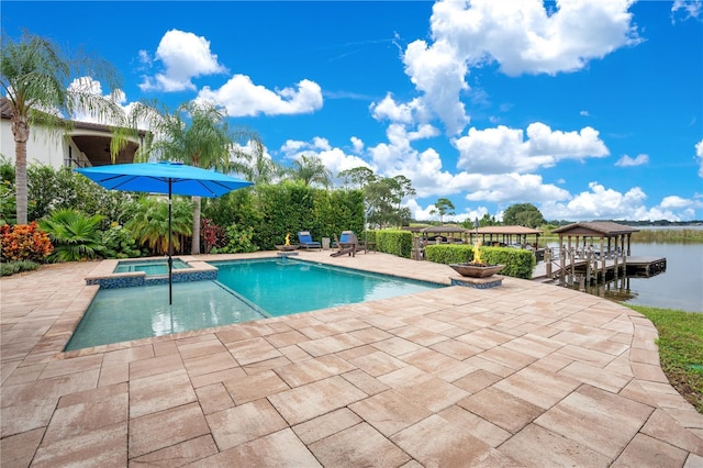 view of pool featuring a pool with connected hot tub, a water view, and a patio