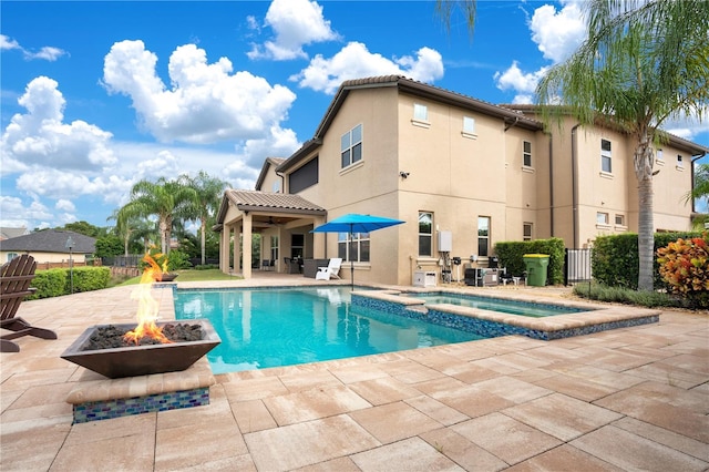 view of swimming pool with an outdoor fire pit, a pool with connected hot tub, a patio area, and fence