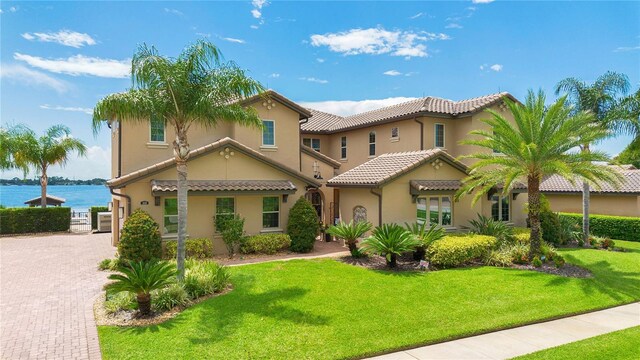 mediterranean / spanish house featuring stucco siding, a front lawn, decorative driveway, and a tiled roof