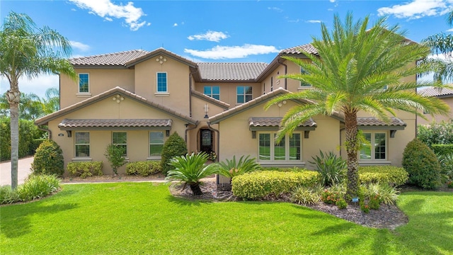 back of house featuring a tile roof, a yard, and stucco siding