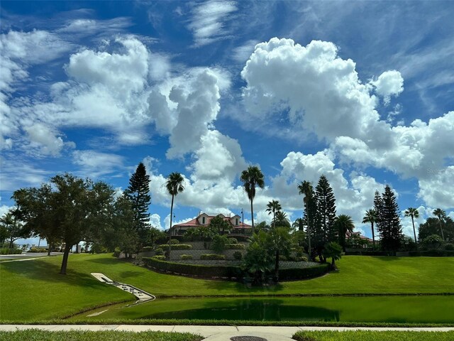 surrounding community with a water view and a lawn