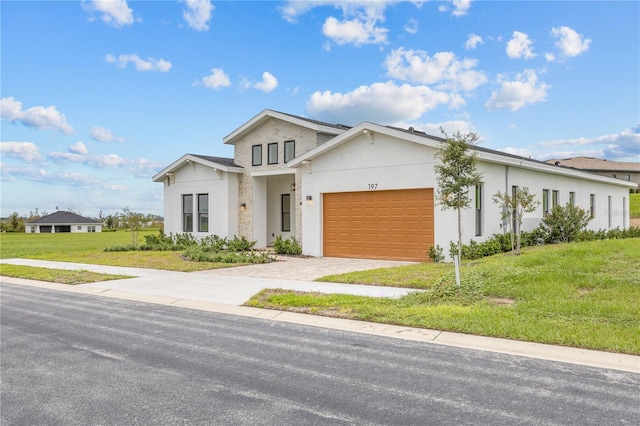 view of front of home featuring decorative driveway, an attached garage, a front lawn, and stucco siding