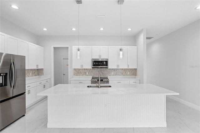 kitchen with decorative backsplash, a kitchen island with sink, stainless steel appliances, pendant lighting, and white cabinetry