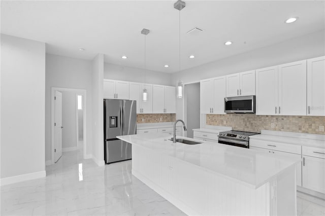 kitchen featuring sink, an island with sink, stainless steel appliances, decorative light fixtures, and white cabinets