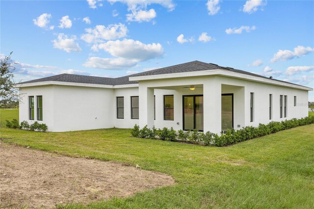 197 Valencia Ridge Dr, Auburndale, FL 33823 - rear view of property with stucco siding, a lawn, a ceiling fan, and a shingled roof