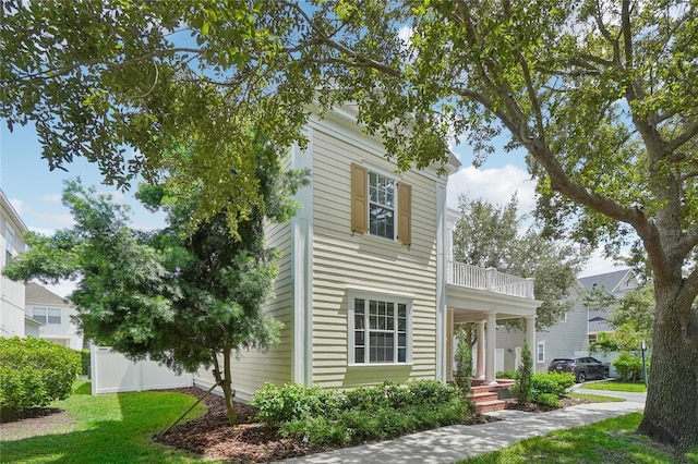 greek revival inspired property featuring a balcony and a front lawn