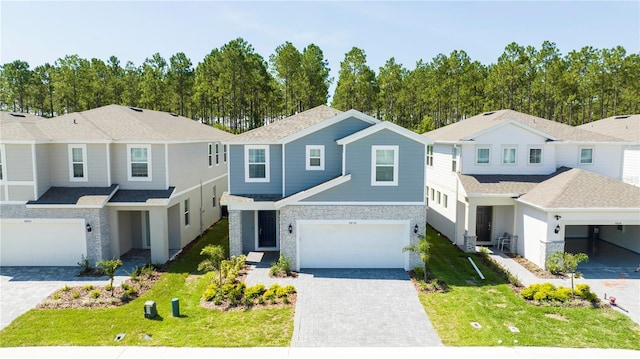 townhome / multi-family property with a garage, a front yard, decorative driveway, and stone siding