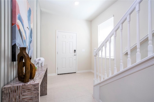 foyer entrance with stairs, light tile patterned floors, and baseboards