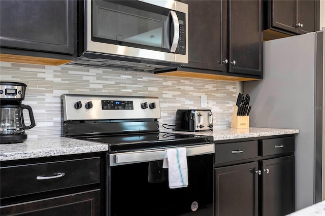 kitchen with backsplash, stainless steel appliances, and light stone countertops