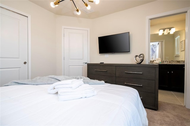 bedroom featuring a notable chandelier, light colored carpet, a closet, and connected bathroom