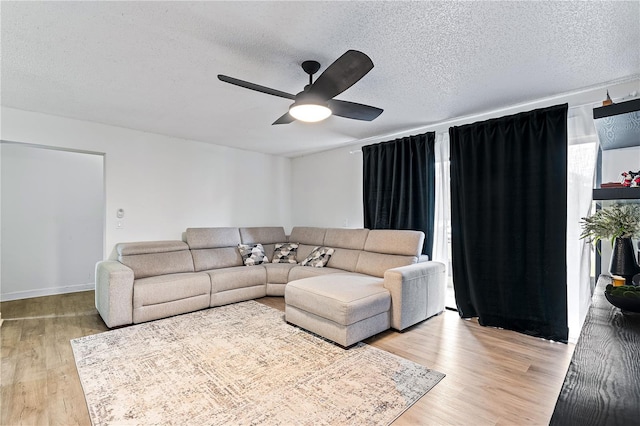 living room featuring a textured ceiling, light hardwood / wood-style flooring, and ceiling fan