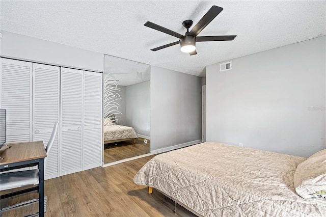 bedroom with a textured ceiling, a closet, ceiling fan, and hardwood / wood-style floors