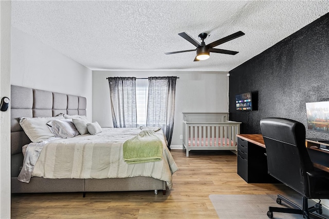 bedroom with hardwood / wood-style floors, ceiling fan, and a textured ceiling